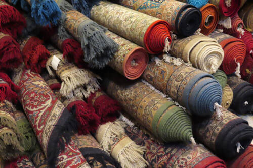 Colourful rolled rugs stacked together.